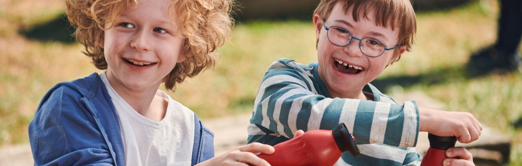 Two smiling boys of primary school age with water bottles on a playground