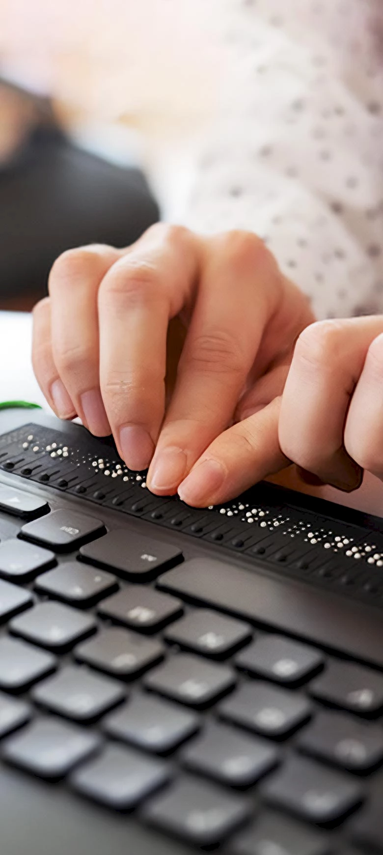 Hände, die einen Computer mit Tastatur und Braillezeile bedienen